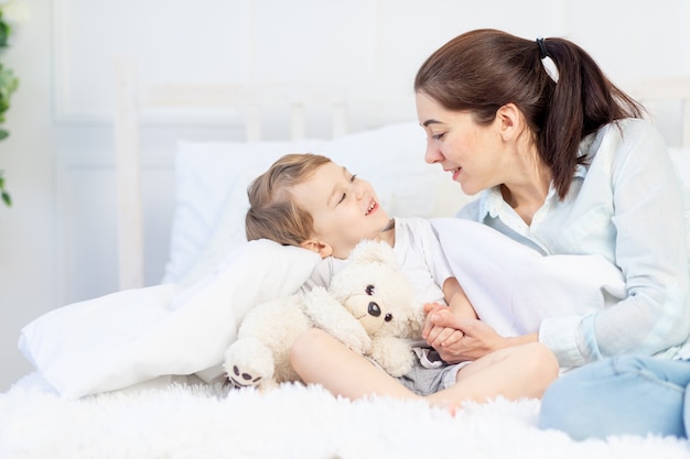 Mamá y bebé hablando en casa en la cama, el concepto de relación entre padres e hijos