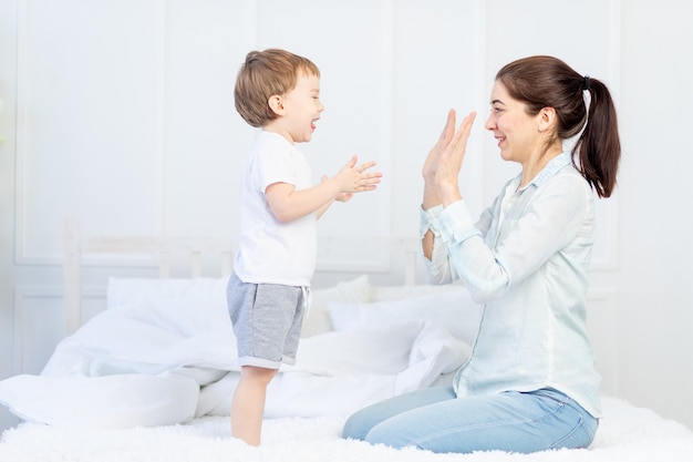 Mamá y bebé juegan en casa en la cama, el concepto de familia y relaciones entre padres e hijos.