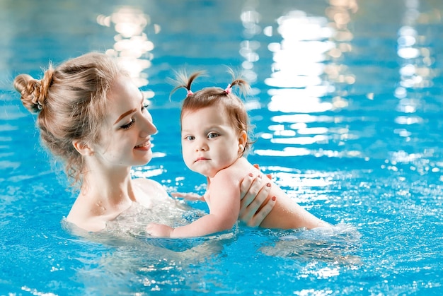 Foto mamá y bebé nadan en la piscina.