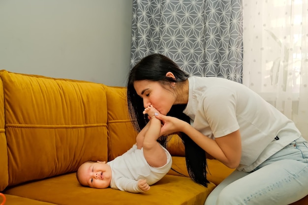 Mamá besa las piernas de un bebé recién nacido el concepto de un beso amor maternal