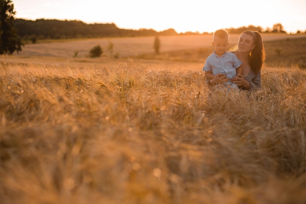 Mamá besa a su hijo en la cabeza en un campo de trigo al atardecer