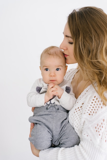 Mamá besa a su pequeño hijo en la cabeza. La alegría de la maternidad y el cuidado del bebé.