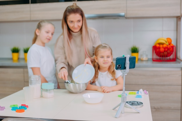 Mama bringt ihren Töchtern bei, in der Küche Teig zu kochen.