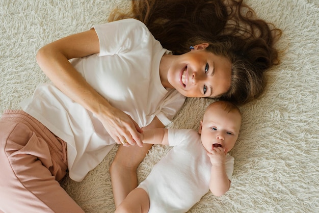 Mamá caucásica se acuesta en la cama con su hijo y sonríe alegremente Vista superior de la familia