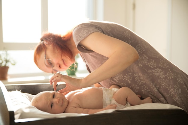 Mamá cuida a su pequeño bebé acostado en una cama