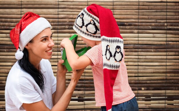 Mamá le da una caja de regalo a su hijo por Navidad.