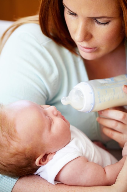 Foto mamá le da leche y alimenta al bebé del biberón para una nutrición saludable desayuno y dieta en la mañana madre hijo y alimentación con fórmula para recién nacidos para el desarrollo del crecimiento y el bienestar juntos en el hogar