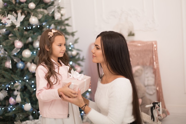 Mamá le da a su amada hija una caja con un regalo de Navidad.