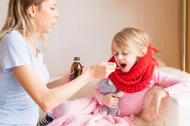 Mamá dando jarabe a su hija enferma