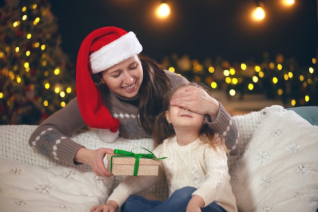 Mamá dando un regalo a su pequeña niña en el sofá