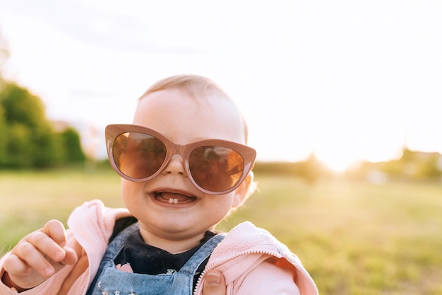 Mama, das Kind spielt im Park, das Kind trägt Mamas Sonnenbrille