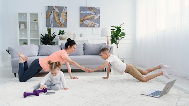 Mamá deportiva con hijo haciendo ejercicio matutino en casa. Madre e hijo hacen ejercicios juntos, concepto de estilo de vida familiar saludable