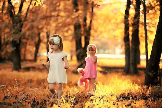 Mamá con dos hijas gemelas a pasear por el parque de otoño