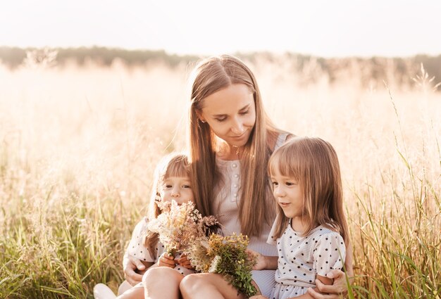 Mamá con dos niñas gemelas jugando en la naturaleza en el verano