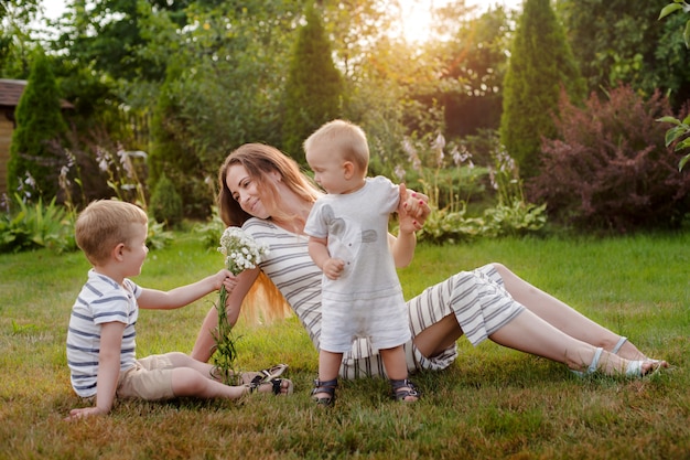 Mamá, dos niños descansan en la naturaleza. La rivalidad entre hermanos. Hermanos, la maternidad.