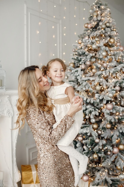 Mamá e hija abrazándose cerca del árbol de Navidad