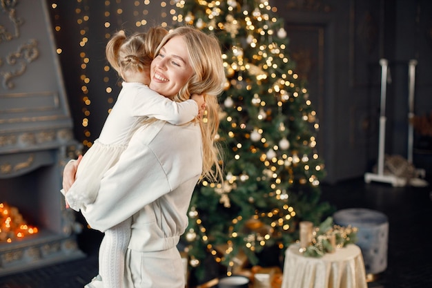 Mamá e hija abrazándose cerca del árbol de Navidad