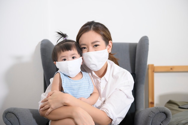 Mamá e hija asiáticas llevan máscara protectora en casa