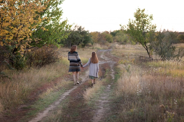 Foto mamá e hija caminan por el prado