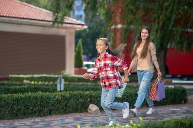 Mamá e hija caminando por la calle con bolsas de la compra.