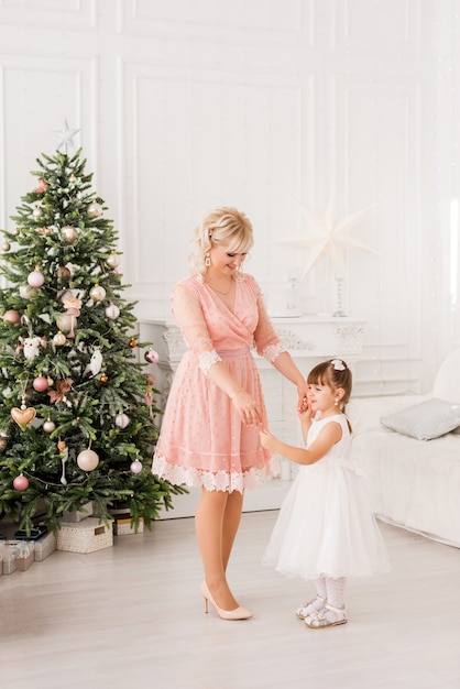 Mamá e hija en casa en el fondo de un árbol de Navidad