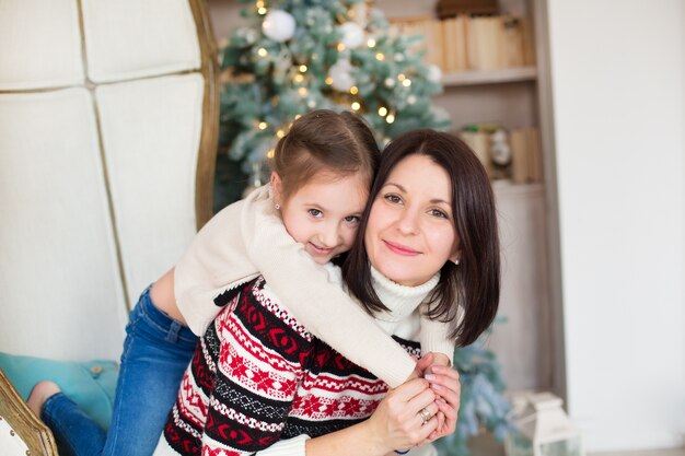 Mamá e hija cerca del árbol de navidad.