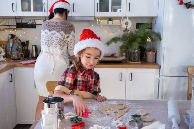 Mamá e hija en la cocina blanca están preparando galletas para Navidad y Año Nuevo Día de la familia preparación para las vacaciones aprender a cocinar pasteles deliciosos cortar formas de masa con moldes