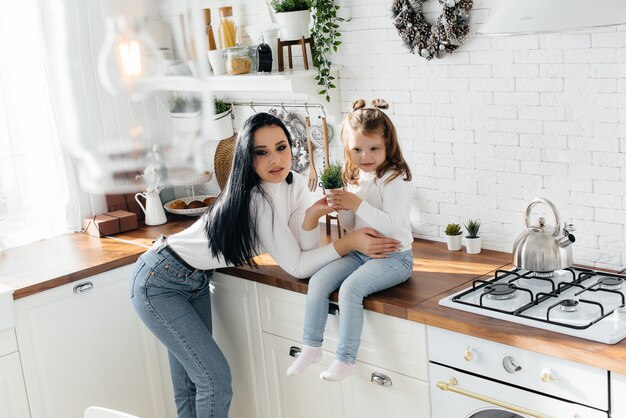 Mamá e Hija cocinan en la cocina y juegan. Familia, felicidad.