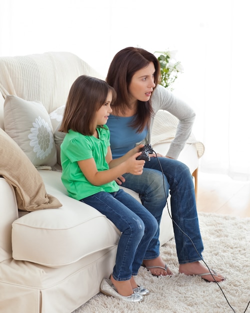 Mamá e hija concentradas jugando videojuegos