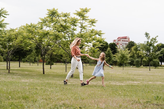 Mamá e hija corren en el parque y se divierten Valores y tradiciones familiares Infancia feliz de un niño La madre juega con su hija