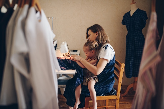 Mamá e hija cosen ropa juntas. Vestido estampado. Máquina de coser eléctrica