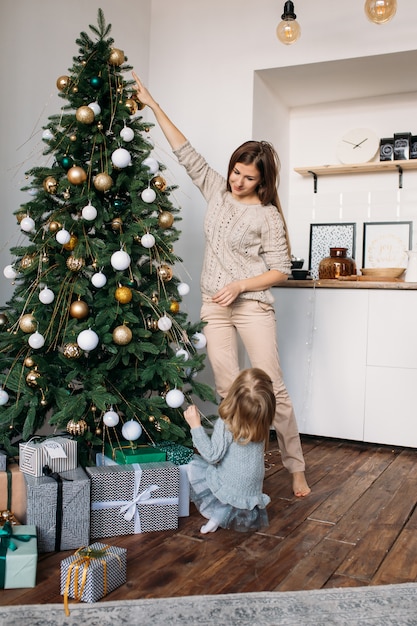 Mamá e hija decoran el árbol de Navidad en el interior.