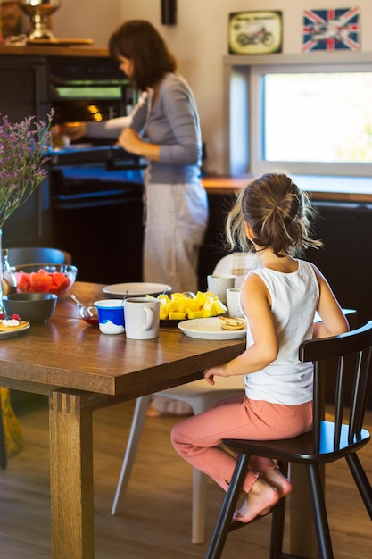 Mamá e hija desayunan en la cocina de casa