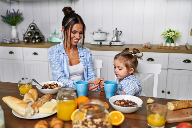 Mamá e hija desayunan en la mañana en casa.