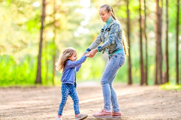 Mamá e hija se divierten en el bosque Día soleado de verano Estado de ánimo juguetón