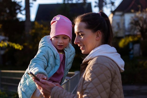 Mamá e hija están mirando algo por teléfono en el parque