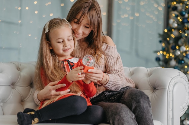 Mamá e hija están sentadas juntas en la casa, esperando la magia navideña. En vísperas de Navidad con mi madre.