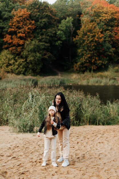 Mamá e hija con estilo en chaquetas de cuero soplan burbujas en un parque de otoño