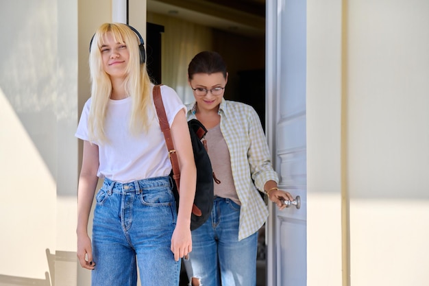 Mamá e hija estudiante en el porche de la casa cerca de la puerta principal