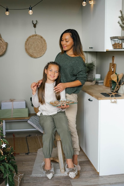 Mamá e hija felices cocinaron galletas de jengibre navideñas en la cocina