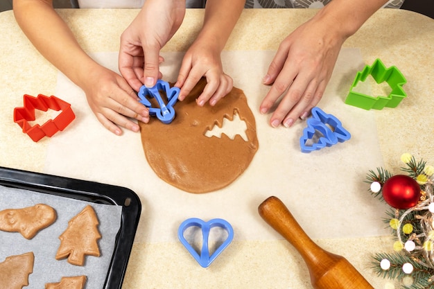 Mamá e hija hacen galletas con masa en la cocina de casa.