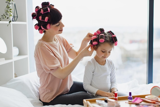 Foto mamá e hija hacen un peinado de moda usando rizos