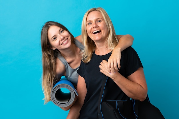 Mamá e hija haciendo yoga aislado en la pared azul