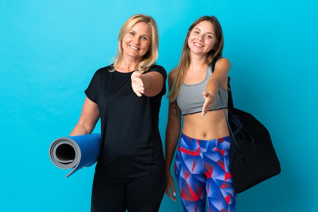 Mamá e hija haciendo yoga dándose la mano para cerrar un buen trato