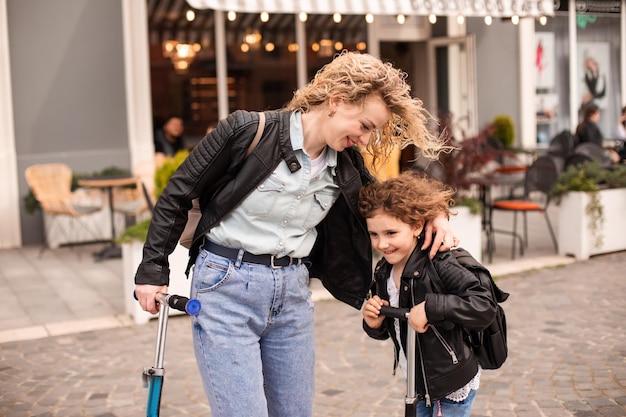 Mamá e hija idénticas con scooters en la ciudad.