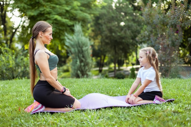 Mamá e hija juegan deportes juntos en una alfombra en el parque Maternidad Pasando tiempo Entrenador de mamá