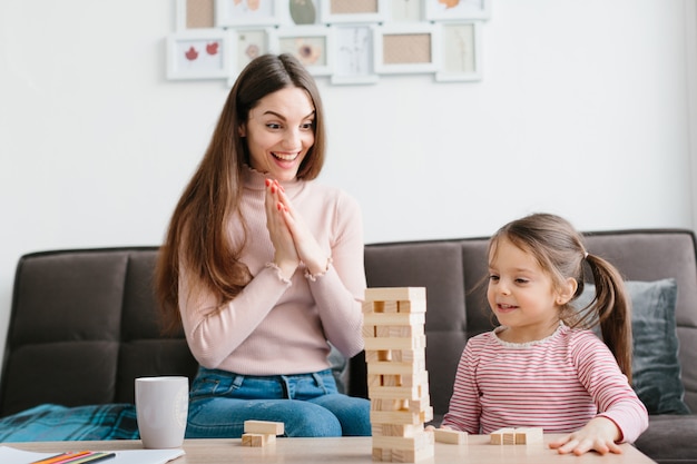 Mamá e hija juegan un juego de mesa en la sala de estar.