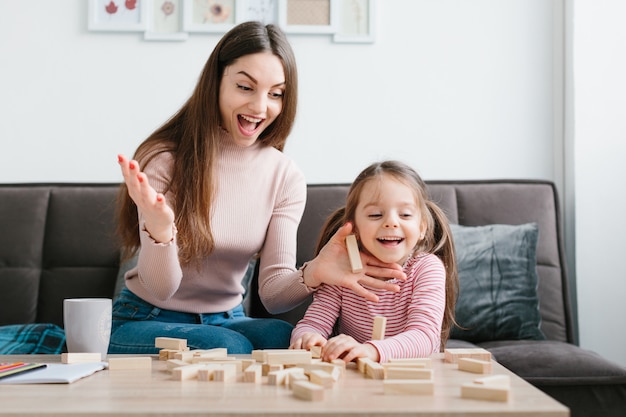 Mamá e hija juegan un juego de mesa en la sala de estar.