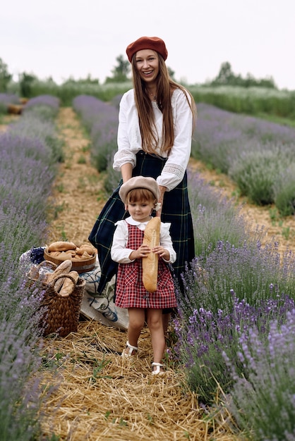 Mamá e hija juntan flores de lavanda en una canasta.