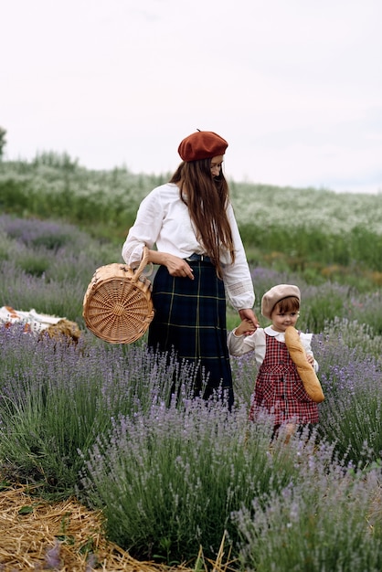 Mamá e hija juntan flores de lavanda en una canasta.